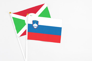 Slovenia and Burundi stick flags on white background. High quality fabric, miniature national flag. Peaceful global concept.White floor for copy space.