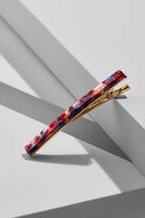 Object shot of a golden alligator hair clip with narrow mother-of-pearl overlay. The pin is in a...