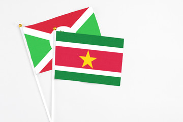 Suriname and Burundi stick flags on white background. High quality fabric, miniature national flag. Peaceful global concept.White floor for copy space.
