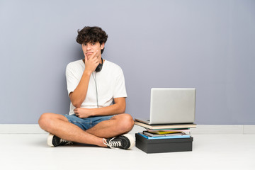 Young man with his laptop sitting one the floor thinking an idea