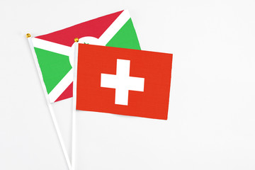Obraz premium Switzerland and Burundi stick flags on white background. High quality fabric, miniature national flag. Peaceful global concept.White floor for copy space.