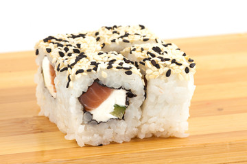 Sushi maki rolls with sesame and tuna on a wooden board.