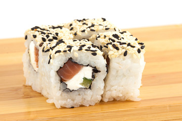 Sushi maki rolls with sesame and tuna on a wooden board.