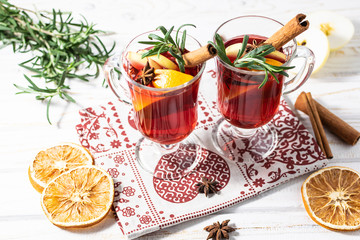 Aromatic hot mulled wine with fruits and spices on the table with traditional Christmas decor.
