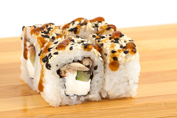 Sushi maki rolls with sesame and eel on a wooden board.