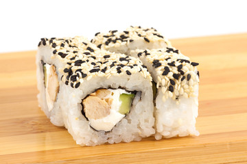 Sushi maki rolls with sesame and chiken on a wooden board.