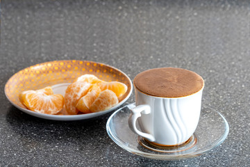 Turkish coffee and mandarin slices on a saucer on a stone table