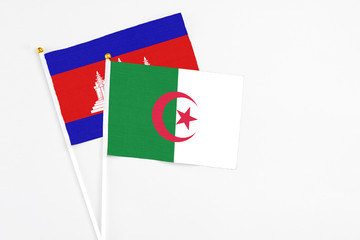 Algeria and Cambodia stick flags on white background. High quality fabric, miniature national flag. Peaceful global concept.White floor for copy space.