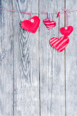 Handmade gingham Love Valentine's hearts on red cord with clips hanging on wooden background, copy space