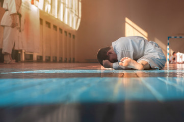 Kids training on karate-do. Young athletes karatekas do warm-up and stretching in the gym on a wooden floor. Banner with space for text. Photo without faces.