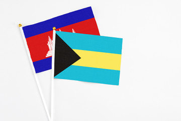 Bahamas and Cambodia stick flags on white background. High quality fabric, miniature national flag. Peaceful global concept.White floor for copy space.