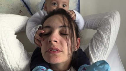 Baby on mother shoulders holding on hair