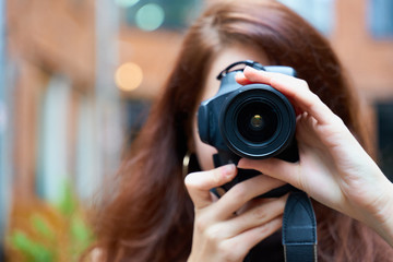 Beautiful stylish fashionable girl holds a camera in her hands and takes pictures. Woman...