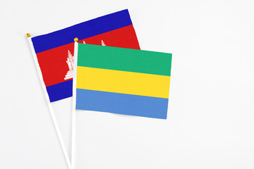 Gabon and Cambodia stick flags on white background. High quality fabric, miniature national flag. Peaceful global concept.White floor for copy space.