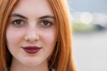 Closeup face portrait of a girl with red hair and clear eyes.