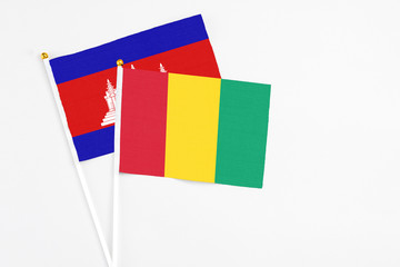 Guinea and Cambodia stick flags on white background. High quality fabric, miniature national flag. Peaceful global concept.White floor for copy space.