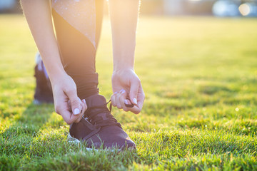 Close-up of female hands tying shoelace on running shoes before practice. Runner getting ready for training. Sport active lifestyle concept.