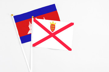 Jersey and Cambodia stick flags on white background. High quality fabric, miniature national flag. Peaceful global concept.White floor for copy space.