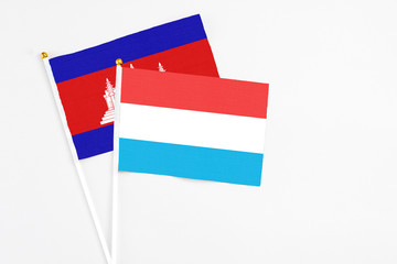 Luxembourg and Cambodia stick flags on white background. High quality fabric, miniature national flag. Peaceful global concept.White floor for copy space.