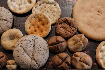 Various kinds of Naan. Famous homemade bread originated from Muslim country. Assorts fresh home made bread on wooden table under warm light.