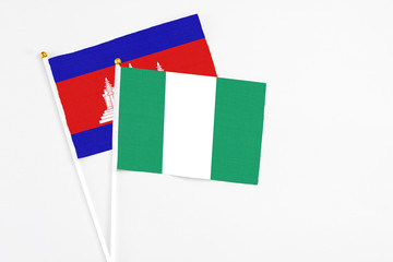 Fototapeta premium Nigeria and Cambodia stick flags on white background. High quality fabric, miniature national flag. Peaceful global concept.White floor for copy space.