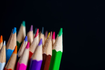 Coloured pencils isolated on black background close up. Vintage look Macro photography. Pencils Wallpaper. Bundle of rainbow colored pencils with selected focus on tips. Multicolored rainbow pencils.