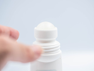 Closeup of Roll-on deodorant with gray background in the bathroom and blurry woman 's hand.