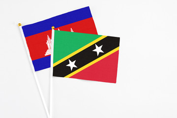Saint Kitts And Nevis and Cambodia stick flags on white background. High quality fabric, miniature national flag. Peaceful global concept.White floor for copy space.