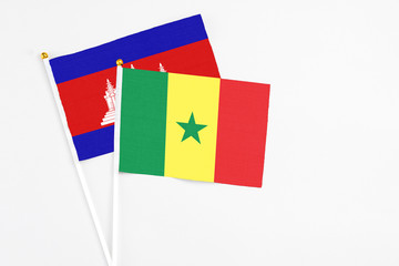 Senegal and Cambodia stick flags on white background. High quality fabric, miniature national flag. Peaceful global concept.White floor for copy space.