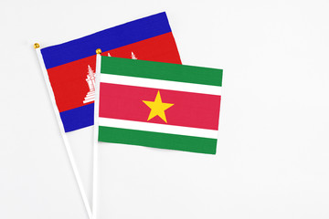 Suriname and Cambodia stick flags on white background. High quality fabric, miniature national flag. Peaceful global concept.White floor for copy space.