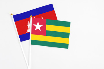 Togo and Cambodia stick flags on white background. High quality fabric, miniature national flag. Peaceful global concept.White floor for copy space.