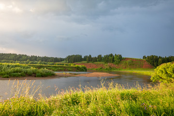 Beautiful summer landscape with green meadows, blue sky, sun and a river
