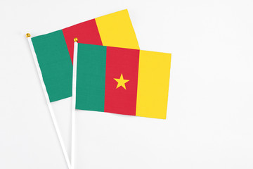 Cameroon and Cameroon stick flags on white background. High quality fabric, miniature national flag. Peaceful global concept.White floor for copy space.