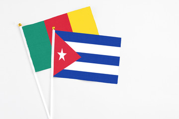 Cuba and Cameroon stick flags on white background. High quality fabric, miniature national flag. Peaceful global concept.White floor for copy space.