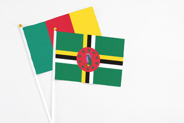 Fototapeta premium Dominica and Cameroon stick flags on white background. High quality fabric, miniature national flag. Peaceful global concept.White floor for copy space.
