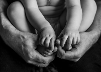 The hands and feet of the baby in men's palms