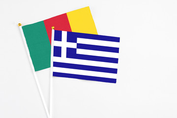 Greece and Cameroon stick flags on white background. High quality fabric, miniature national flag. Peaceful global concept.White floor for copy space.
