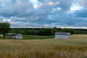 White barn in a field with sky and clouds in the background