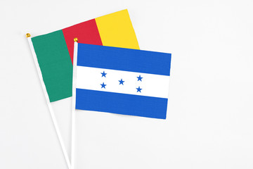 Honduras and Cameroon stick flags on white background. High quality fabric, miniature national flag. Peaceful global concept.White floor for copy space.