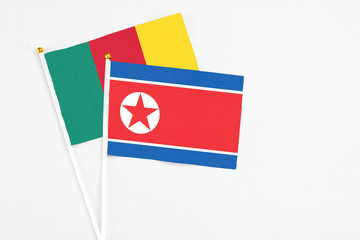 North Korea and Cameroon stick flags on white background. High quality fabric, miniature national flag. Peaceful global concept.White floor for copy space.