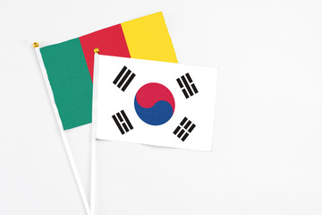 South Korea and Cameroon stick flags on white background. High quality fabric, miniature national flag. Peaceful global concept.White floor for copy space.