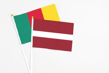 Latvia and Cameroon stick flags on white background. High quality fabric, miniature national flag. Peaceful global concept.White floor for copy space.