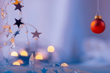 Eine rote hängende Weihnachtskugel mit Lichterkette und Sternen
