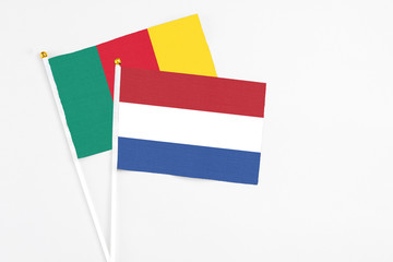 Netherlands and Cameroon stick flags on white background. High quality fabric, miniature national flag. Peaceful global concept.White floor for copy space.