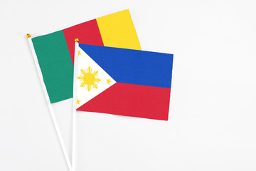 Philippines and Cameroon stick flags on white background. High quality fabric, miniature national flag. Peaceful global concept.White floor for copy space.