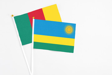 Rwanda and Cameroon stick flags on white background. High quality fabric, miniature national flag. Peaceful global concept.White floor for copy space.