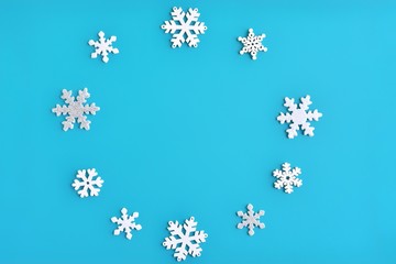 Blue Christmas background with shiny silver and white snowflakes border and empty space for  text, selective focus. New year flat lay with snowflakes decorative border. Winter postcard