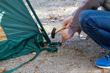 キャンプ場でテントのペグを打つ男性