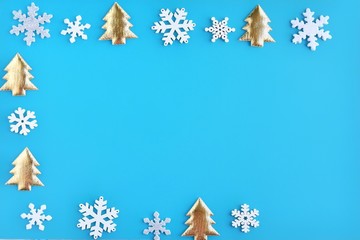Fototapeta na wymiar Turquoise Christmas background with white snowflakes and golden new year tree border and empty space for text, selective focus. New year flat lay with snowflakes and fir decorative border. Winter pos