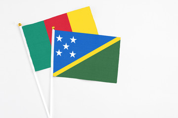 Solomon Islands and Cameroon stick flags on white background. High quality fabric, miniature national flag. Peaceful global concept.White floor for copy space.